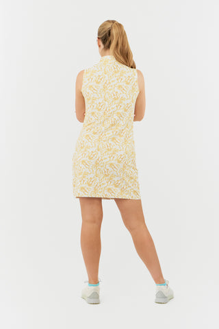 The Pure Golf model features the back of the Miley Sleeveless dress, showcasing our sunkissed print in warm honey hues. Crafted from 4-way stretch fabric for optimal flexibility and freedom of movement, it includes detachable shorts for added versatility and coverage. The dress provides a flattering fit for all body types. The mock neck collar offers a sleek look. Designed to be anti-crease, anti-static, and quick-drying, the dress offers UPF 50+ protection. It is made from 95% Polyester and 5% Spandex.