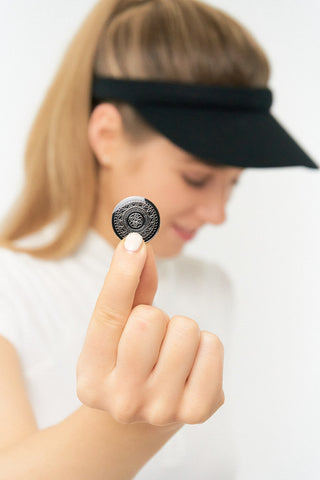 Black Clip ladies golf visor constructed with quick-drying fabrics. The visor comes in a one size fits all design which clips around your head to hold it securely in place. It also features a concealed magnet  in peak with a hand enamelled lace effect golf ball marker attached, making it a lovely golf accessory, golf gift! The headband features a soft lined absorbent towel. 