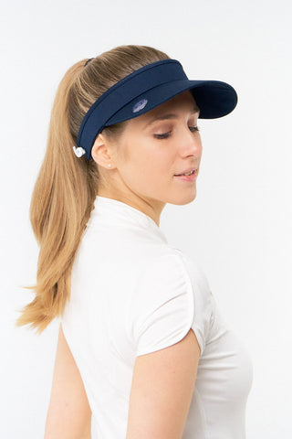 Navy ladies golf visor constructed with quick-drying fabrics. The visor comes in a one size fits all design with an elasticated cord at the rear to hold it securely in place. It also features a concealed magnet  in peak with a hand enamelled lace golf ball marker attached, making it a lovely golf accessory, golf gift! The headband features a soft lined absorbent towel. 