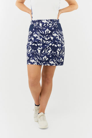 The Pure Golf lifestyle shot of the Accuracy Skort with Side Zip in Wild Peony Navy highlights a beautiful botanical print in navy and white. Crafted from 4-way stretch material, this skort offers flexibility and unrestricted movement, while the detachable shorts provide added  coverage. The convenient side zipper closure ensures easy wear, and the stylish back panel adds a flattering touch. Designed with anti-crease, anti-static, and quick-drying properties, it also offers UPF 50+,made from 100% Polyester.