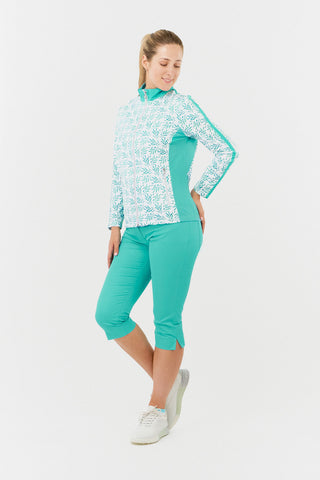 The model shot of the Pure Golf Gella Ladies Golf Mid Layer Jacket in Floating Palms White showcases a bold botanical print set against a clean white backdrop, with ocean block color accents on the mock neck, sides, and a thin stripe down each arm. This regular-fit polo offers 4-way stretch for a flattering fit on all body types. Made from 95% Polyester and 5% Spandex, the jacket is designed to be anti-crease, anti-static, and quick-drying, UPF 50+. Paired with Trust Capri's in Ocean. 