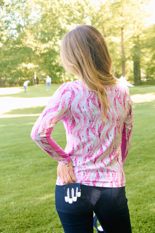 The Pure Golf Balance long-sleeve ladies' golf zip top in Rose Water, shown in a back lifestyle shot, features layers of delicate petals in shades of pink. Designed with a regular fit, it provides 4-way stretch for comfort and flexibility on all body types. The mock neck collar adds a sleek touch, while the mesh sleeve panels enhance breathability. Made from 95% Polyester and 5% Spandex, the top is anti-crease, anti-static, quick-drying, and offers UPF 50+ sun protection.